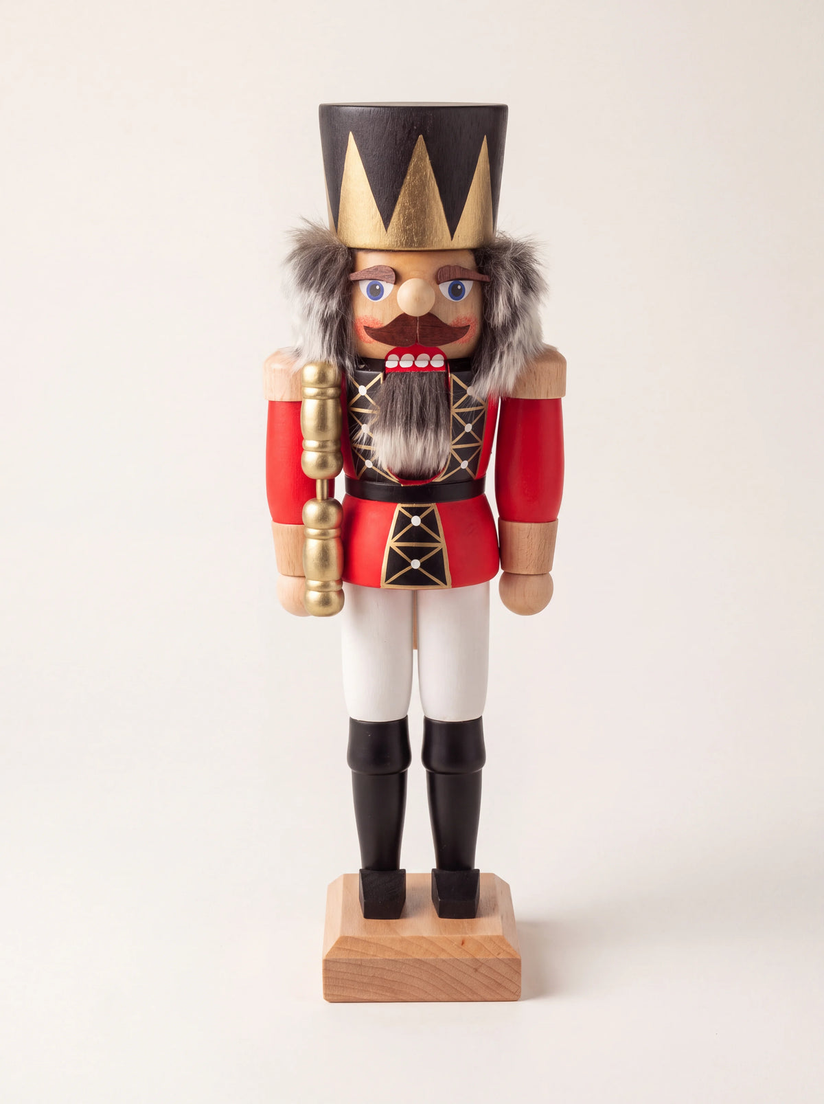 Red wooden king nutcracker with a pointed gold crown, grey faux-fur hair and beard, and a golden sceptre