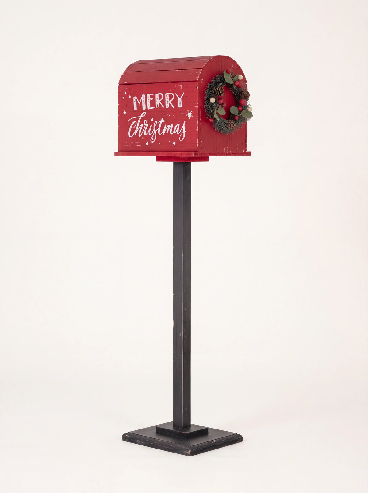 Red wooden post box on a dark stand with Merry Christmas lettering and a small wreath