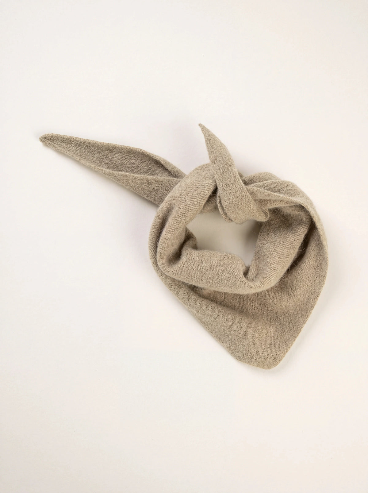 Triangular knitted wool bandana in clay beige, tied loosely with tapered ends