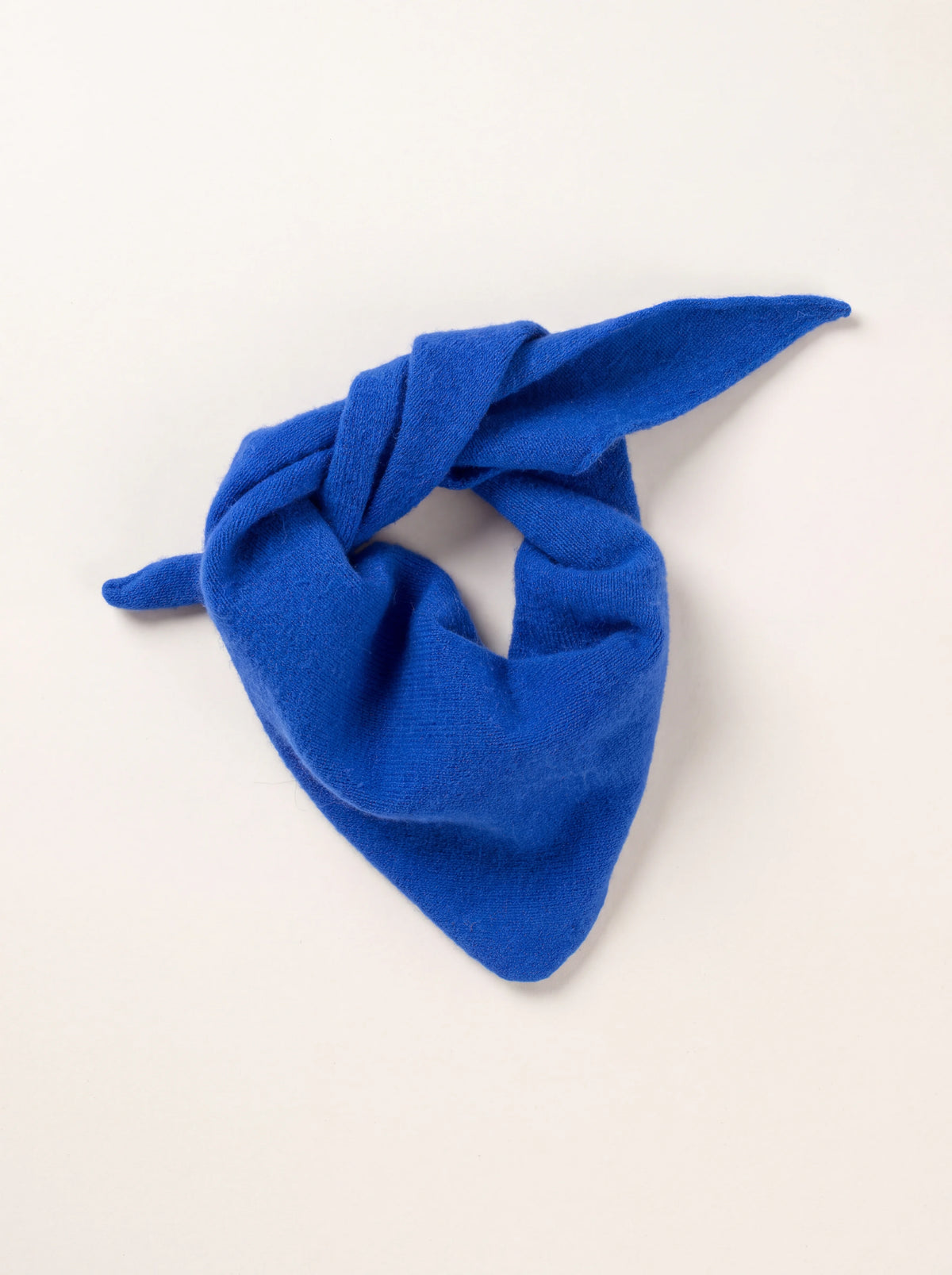 Royal blue knitted wool bandana loosely tied into a neckerchief shape with tapered ends