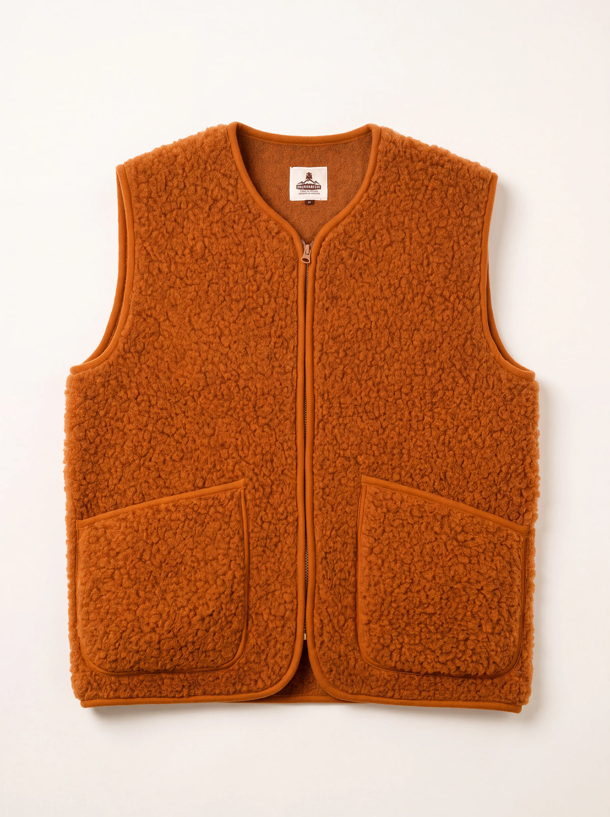 Rust orange merino wool fleece vest with a front zip, piped edges and two patch pockets