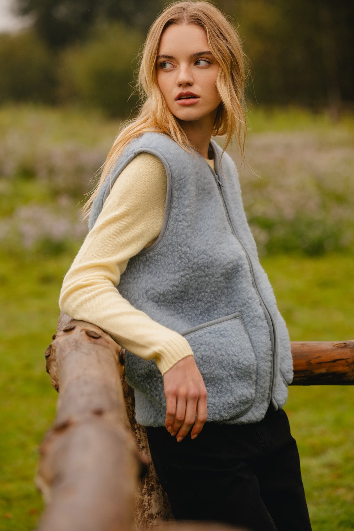 Side view of the wool fleece vest, highlighting the curly texture, front patch pocket and piped armhole