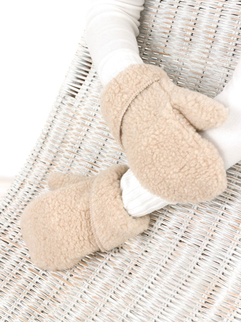 Beige wool mittens with a textured fleece finish and folded cuffs, worn on hands