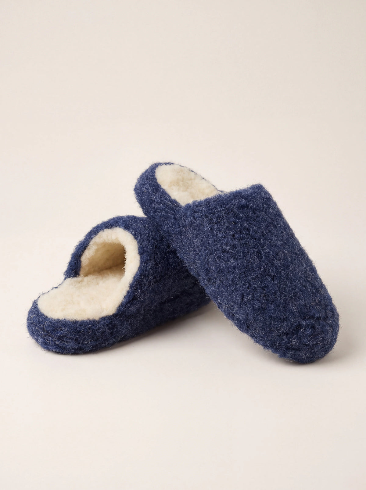Dark blue sheep wool mule slippers with rounded toes and contrasting cream fleece lining