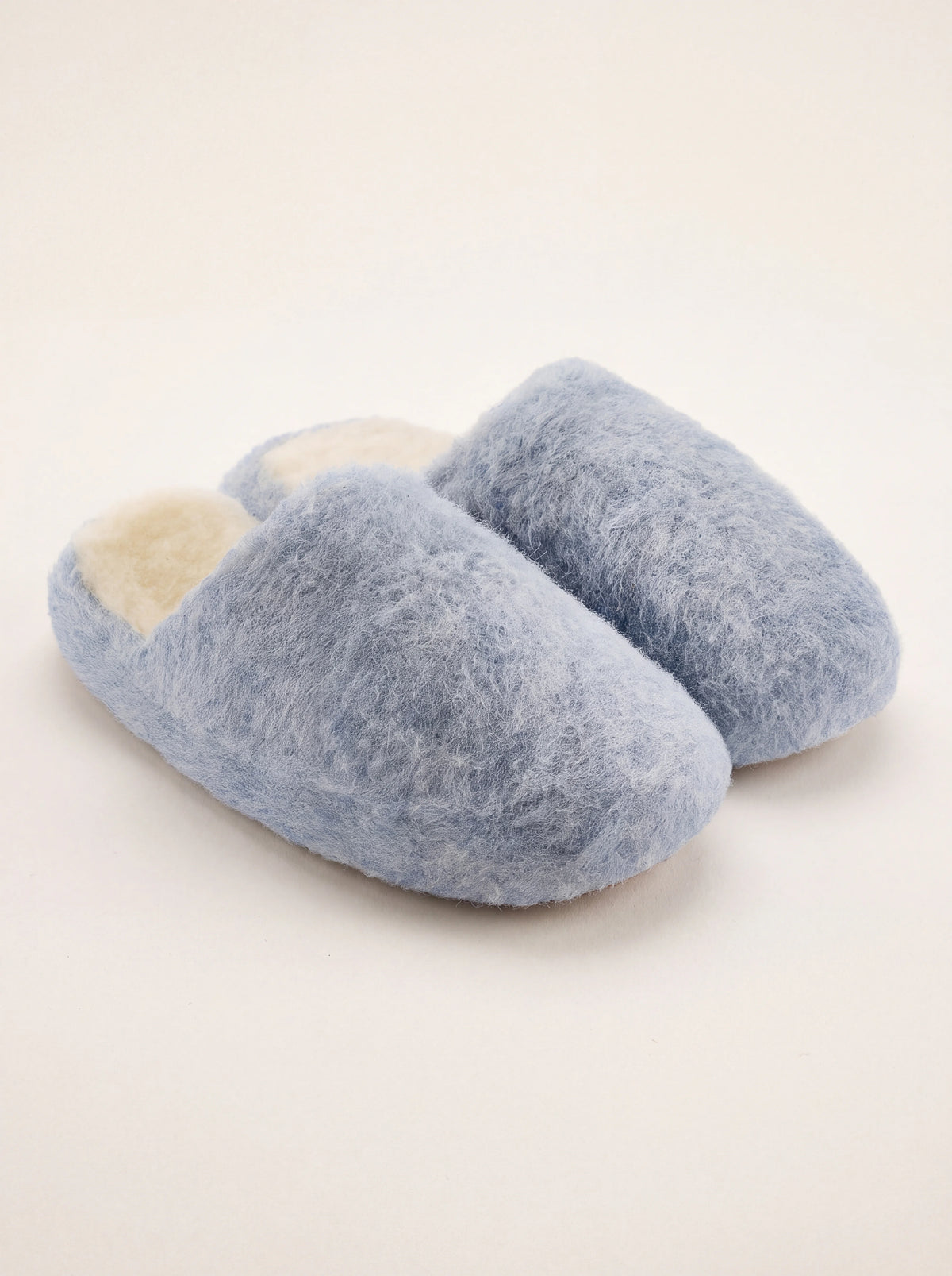 Light blue sheep wool mule slippers with a fluffy exterior and cream-coloured lining