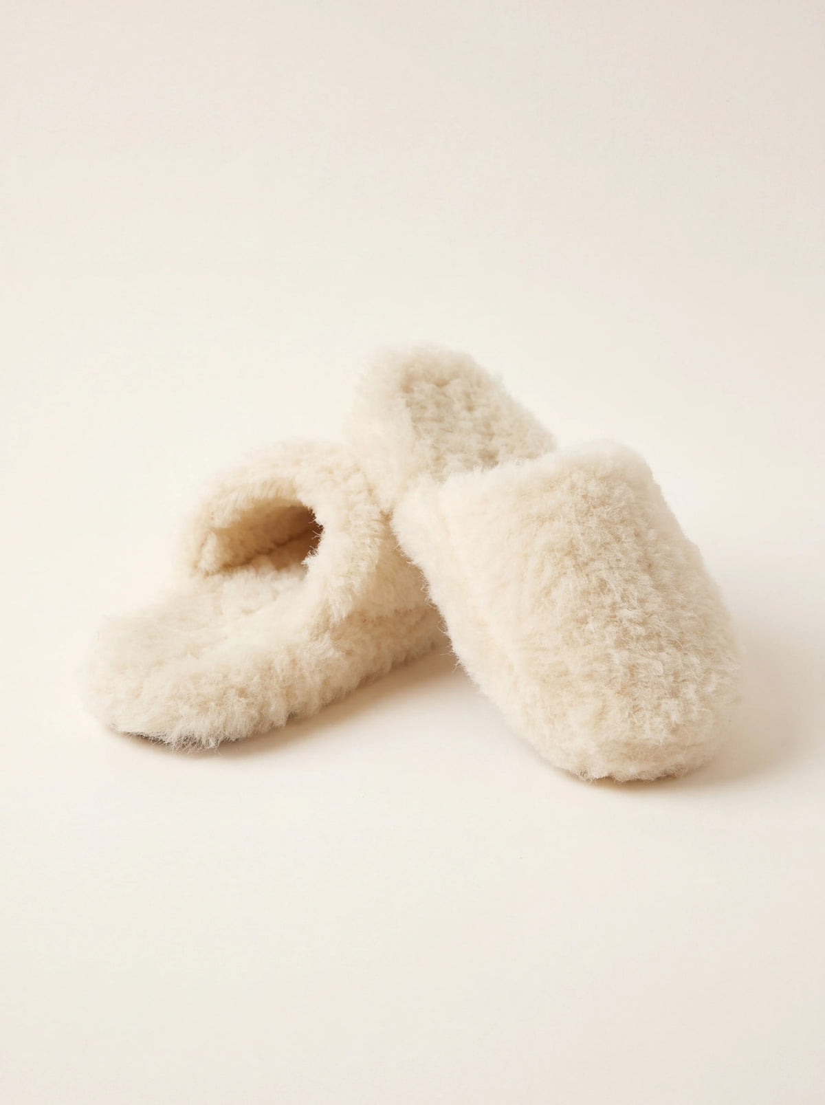 Fluffy natural sheep wool mule slippers in off-white with rounded toes and open backs