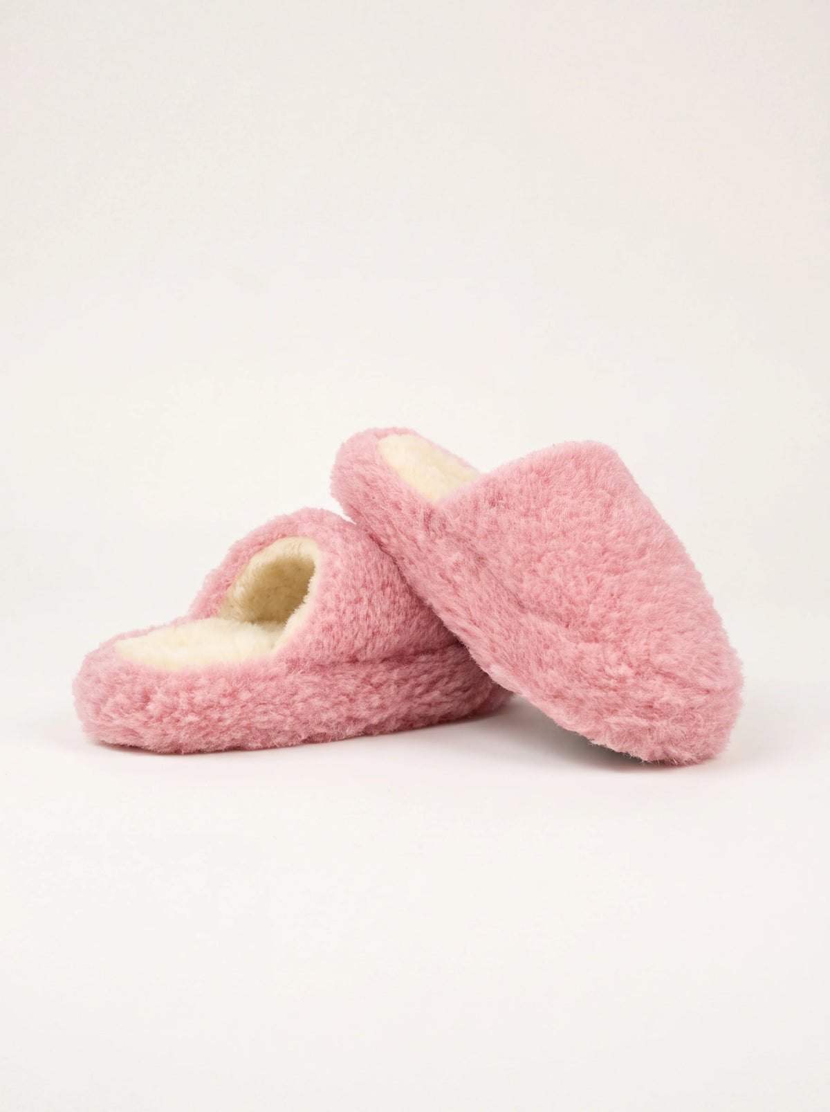 Pink sheep wool mule slippers with a fluffy texture and cream footbed