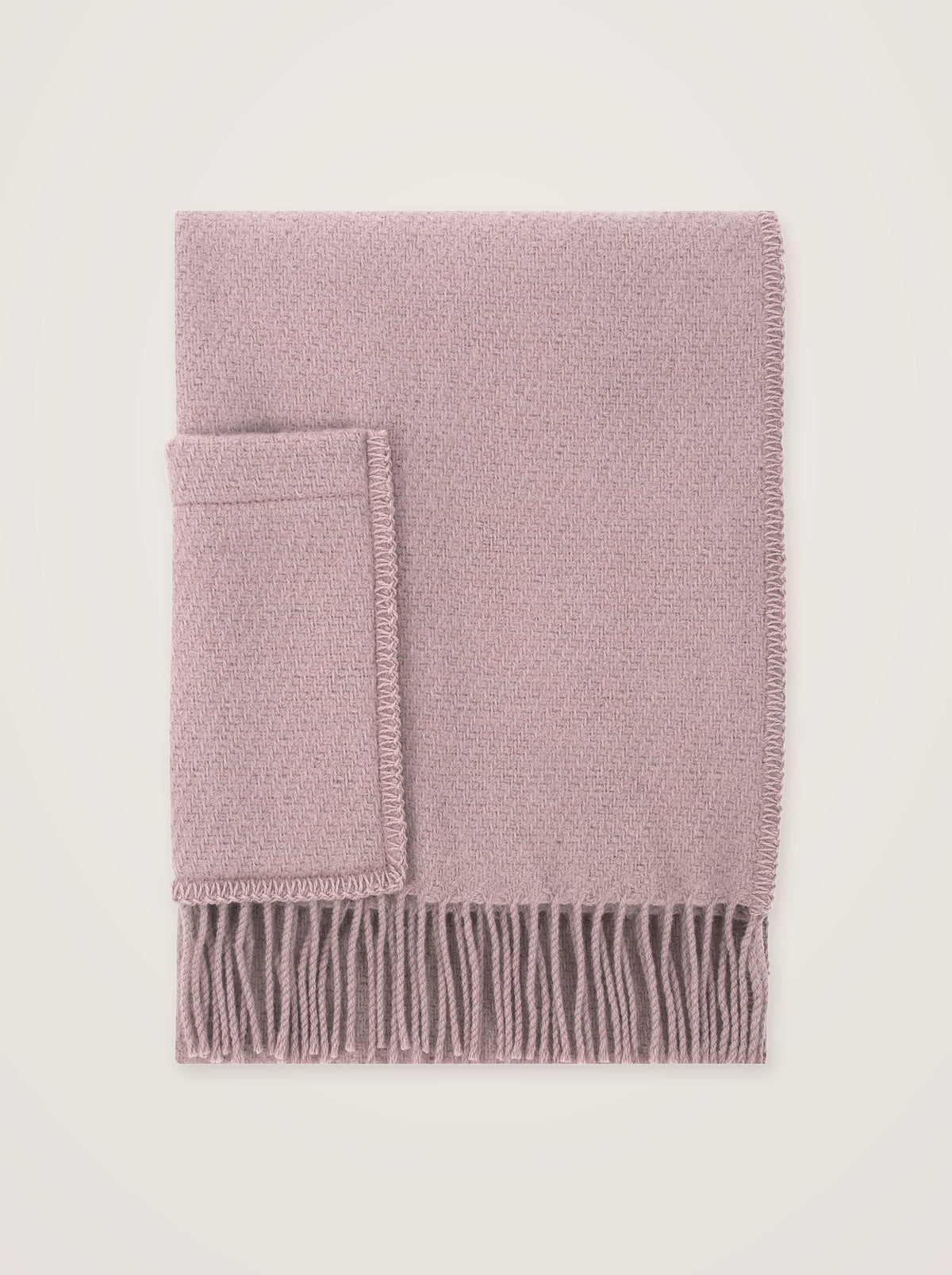 Dusty rose wool pocket shawl neatly folded flat, showing its woven texture, patch pocket and fringed hem