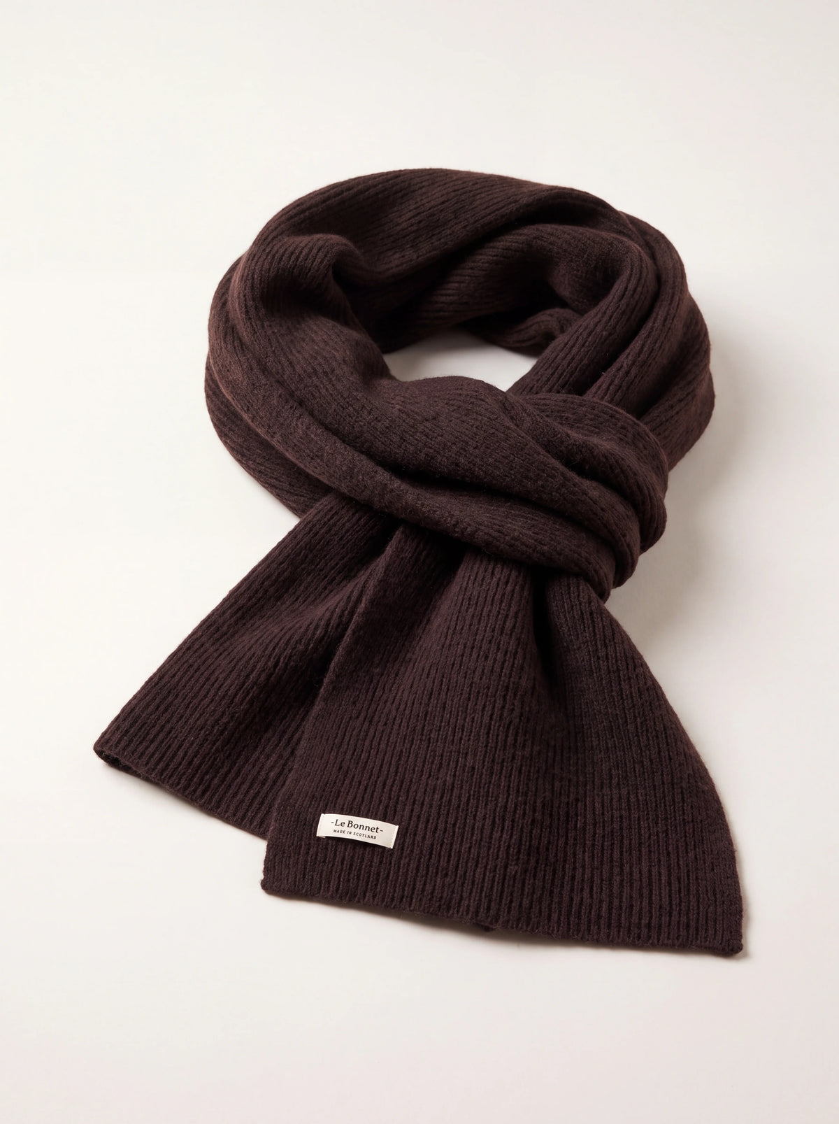 Espresso brown ribbed wool scarf looped in a knot, with a label reading -Le Bonnet- MADE IN SCOTLAND