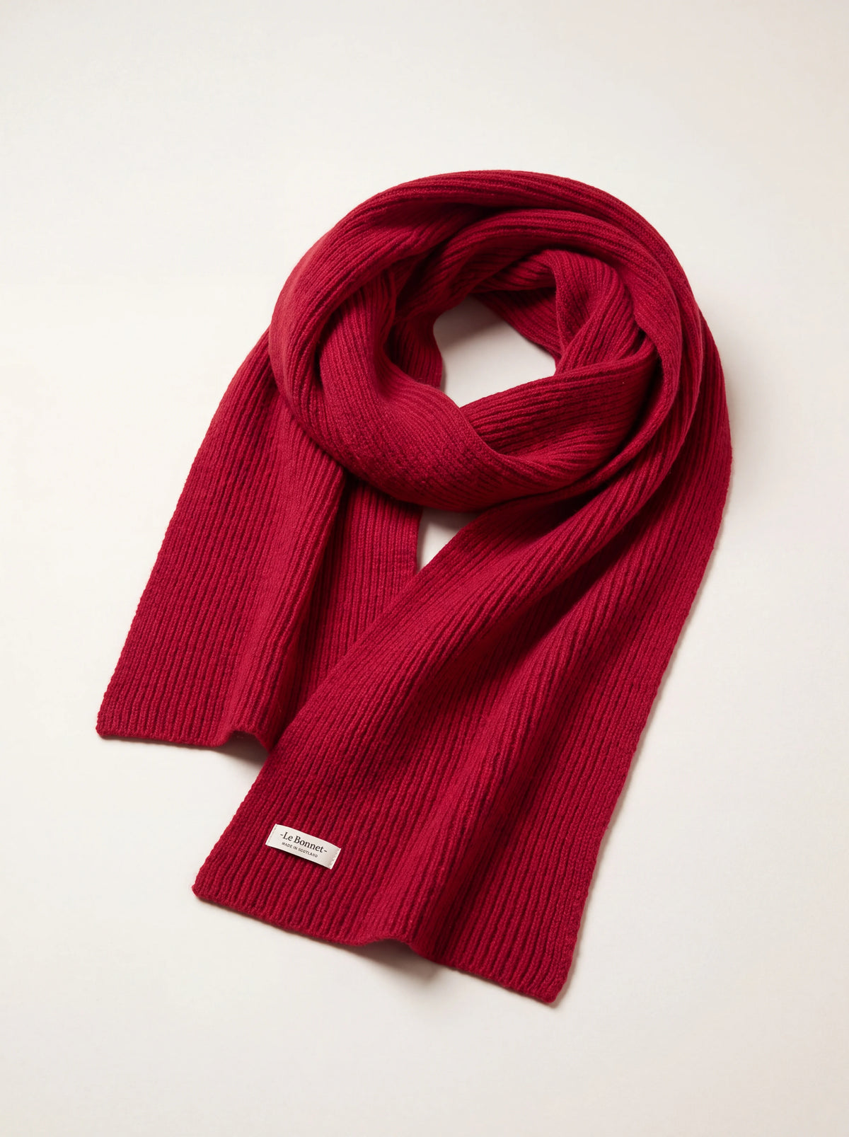 Framboise red ribbed wool scarf looped with a hem label reading '-Le Bonnet- MADE IN SCOTLAND