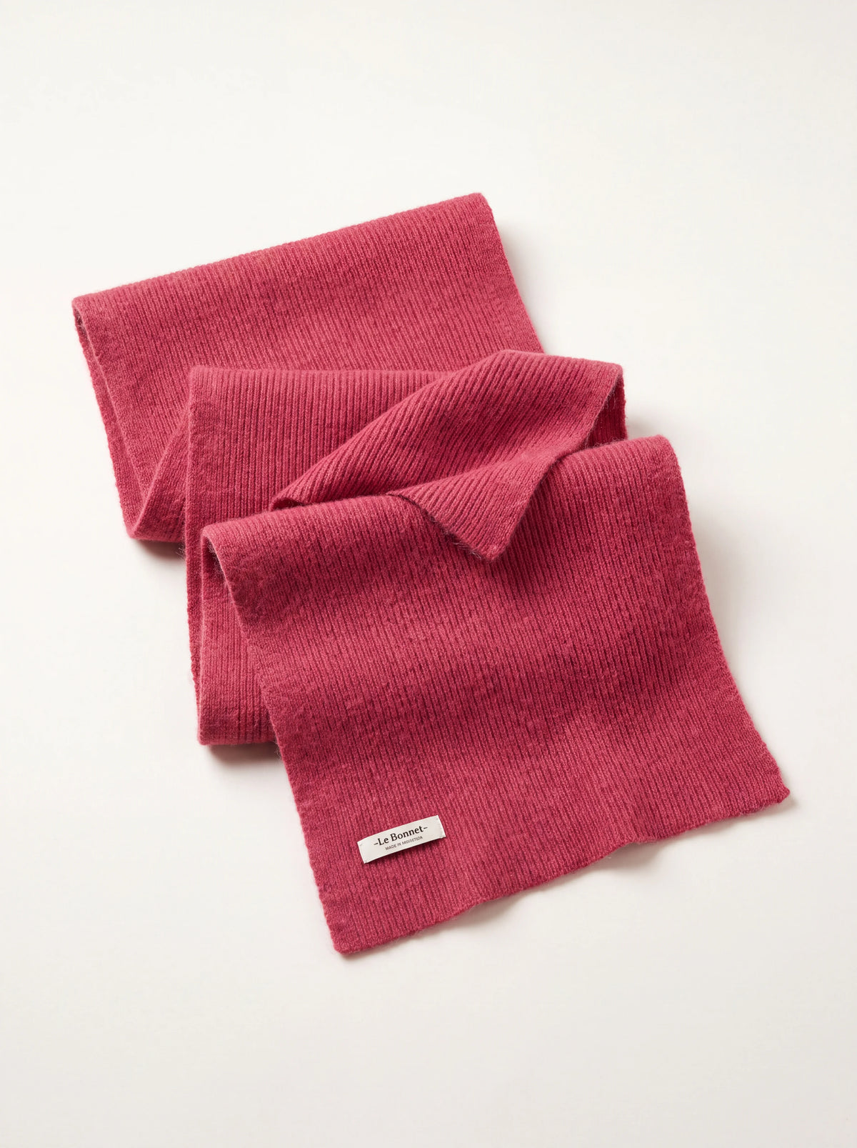 Ribbed fuchsia wool scarf folded into layers, with a woven '-Le Bonnet-' label at the hem