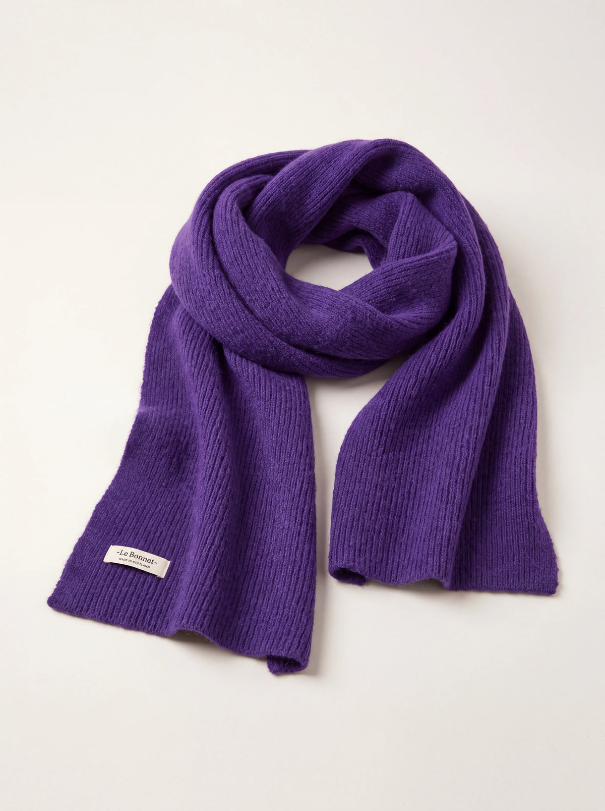 Grape purple ribbed lambswool scarf draped in a loop, with a sewn label reading '-Le Bonnet- MADE IN SCOTLAND