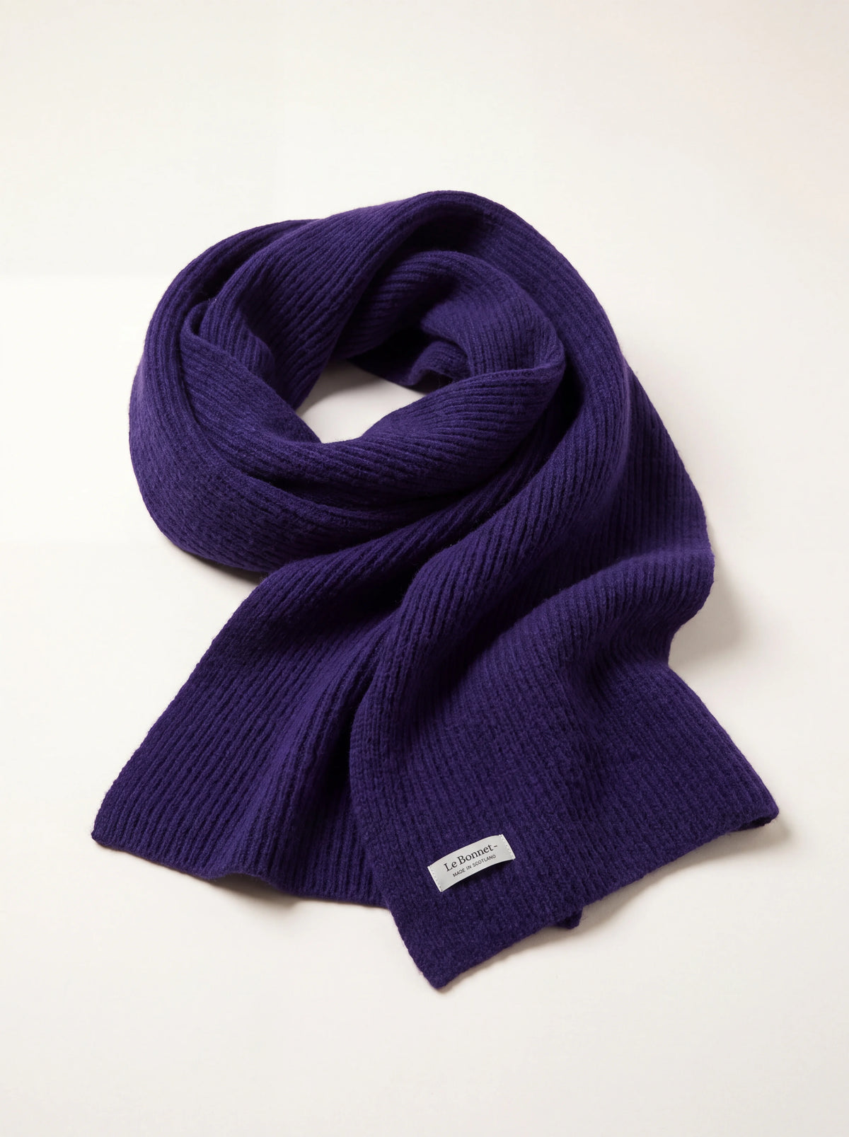 Indigo ribbed wool scarf loosely looped, with a white Le Bonnet - MADE IN SCOTLAND label