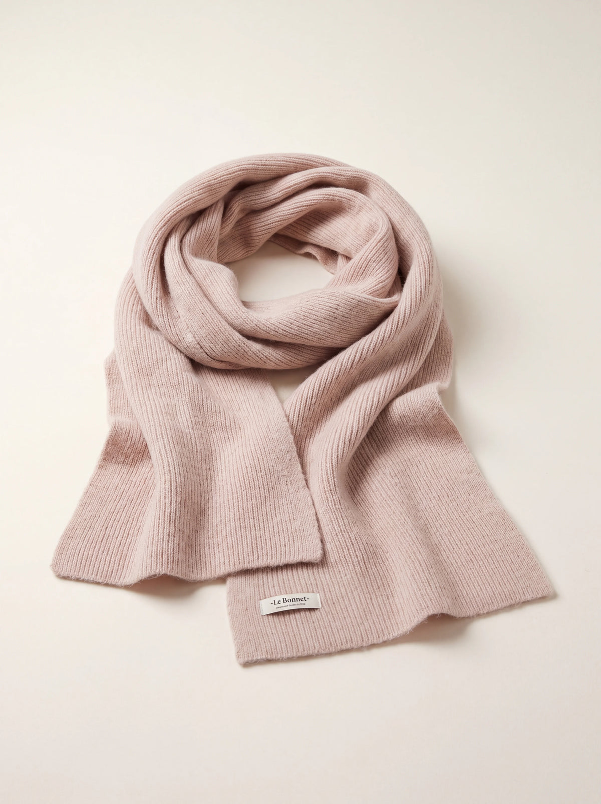 Ribbed wool scarf in misty rose pink, loosely looped with a white -Le Bonnet- label stitched near the hem