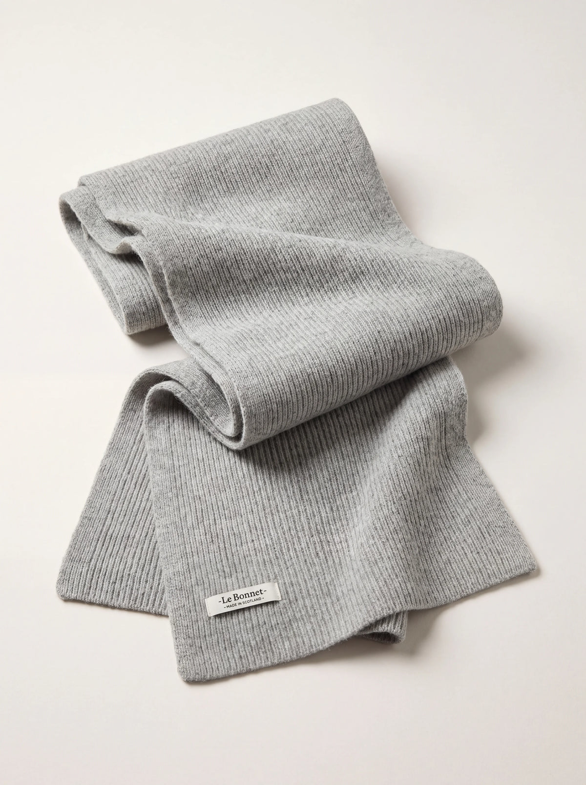 Silver ribbed wool scarf loosely folded, with a stitched hem label reading -Le Bonnet- MADE IN SCOTLAND-