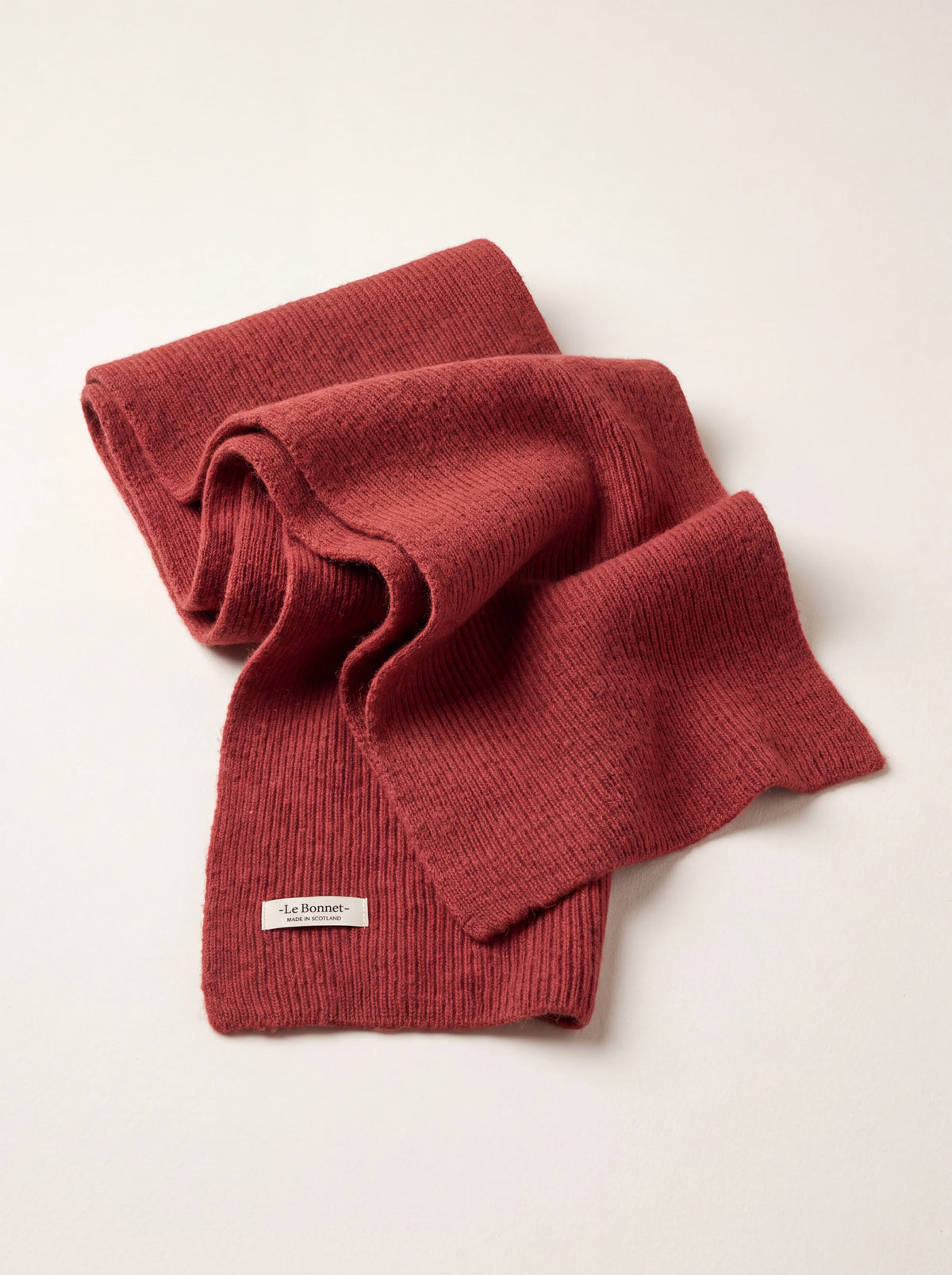 Ribbed terracotta wool scarf, folded with a woven label reading -Le Bonnet- MADE IN SCOTLAND