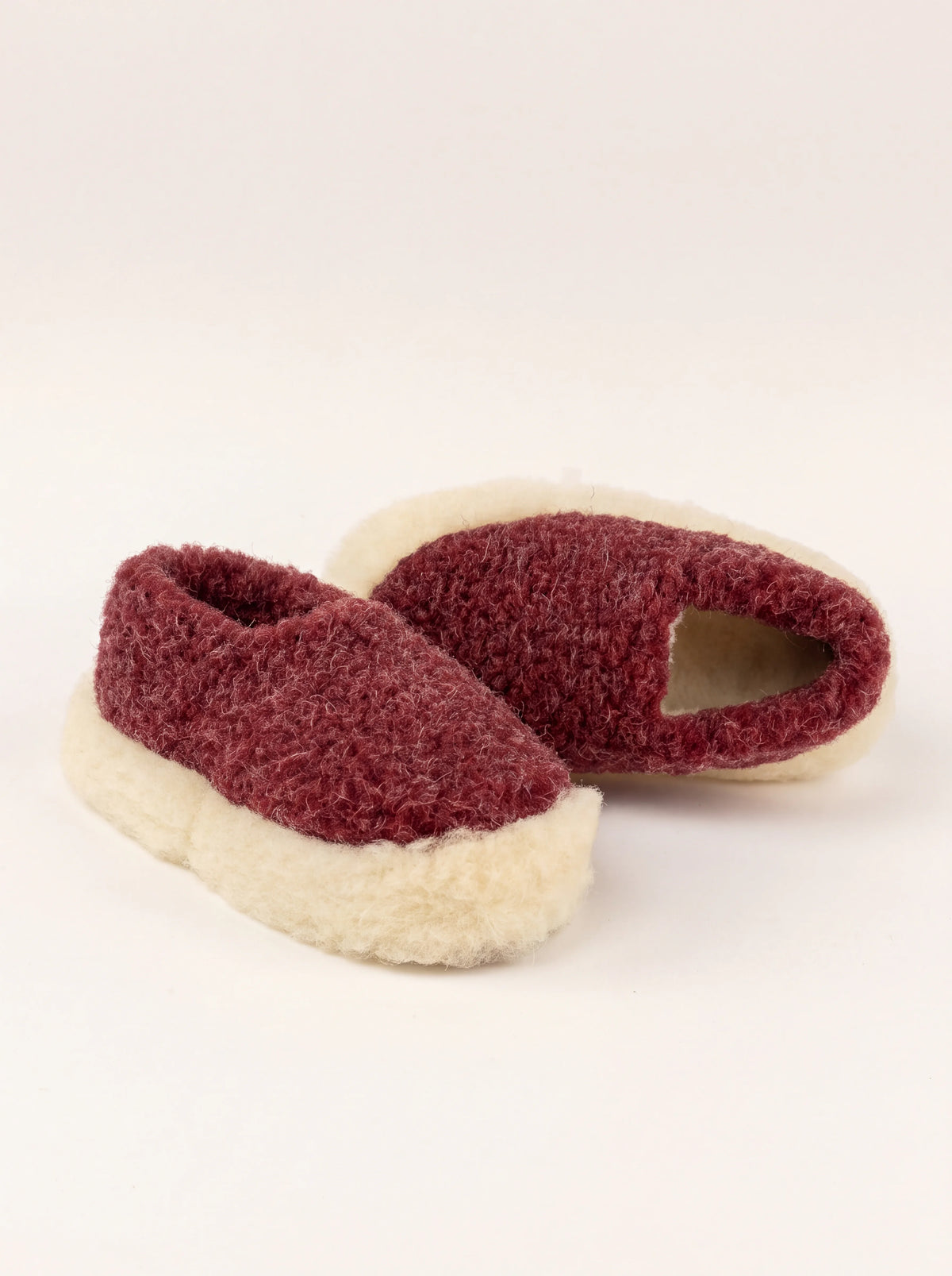 Dark red sheep wool slippers with textured curly uppers and thick off-white fleece trim