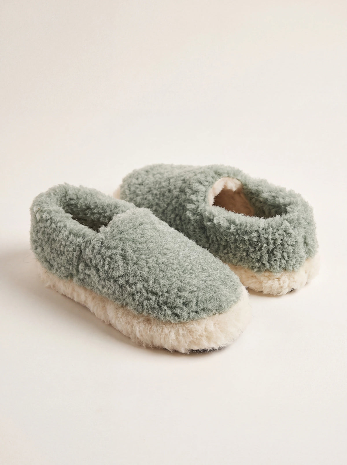 Sage green sheep wool slippers with a fleece texture, closed backs and thick off-white trim