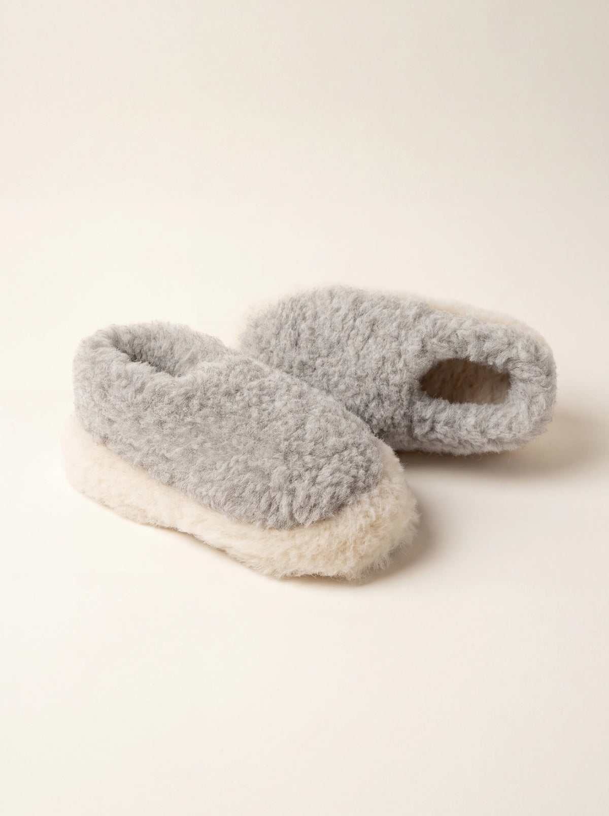 Pair of light grey sheep wool slippers with contrasting off-white trim and closed backs