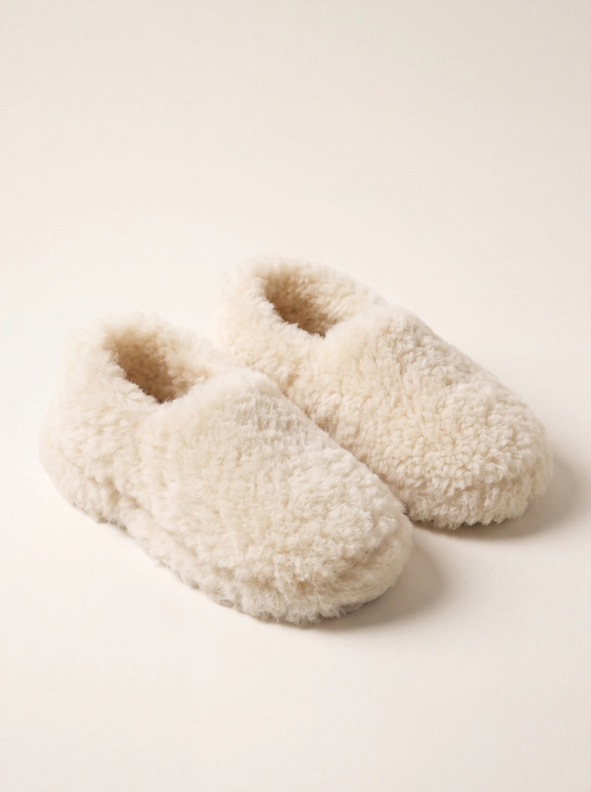 Pair of off-white sheep wool slippers with closed backs and rounded toes