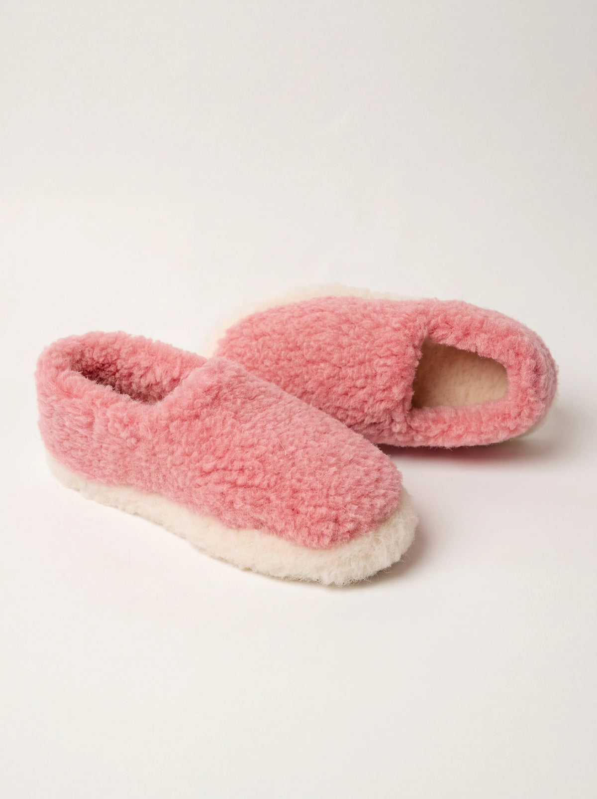 Pink sheep wool slippers with textured fleece finish, enclosed heels and off-white bases