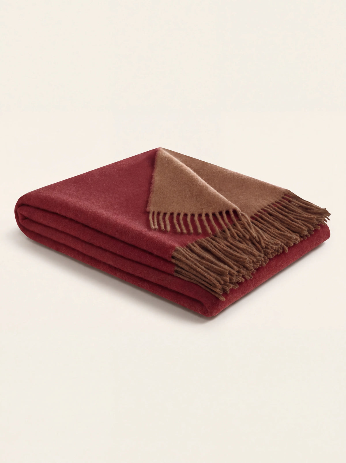 Folded dark red wool and cashmere throw showing the cashew brown reverse and fringed edge