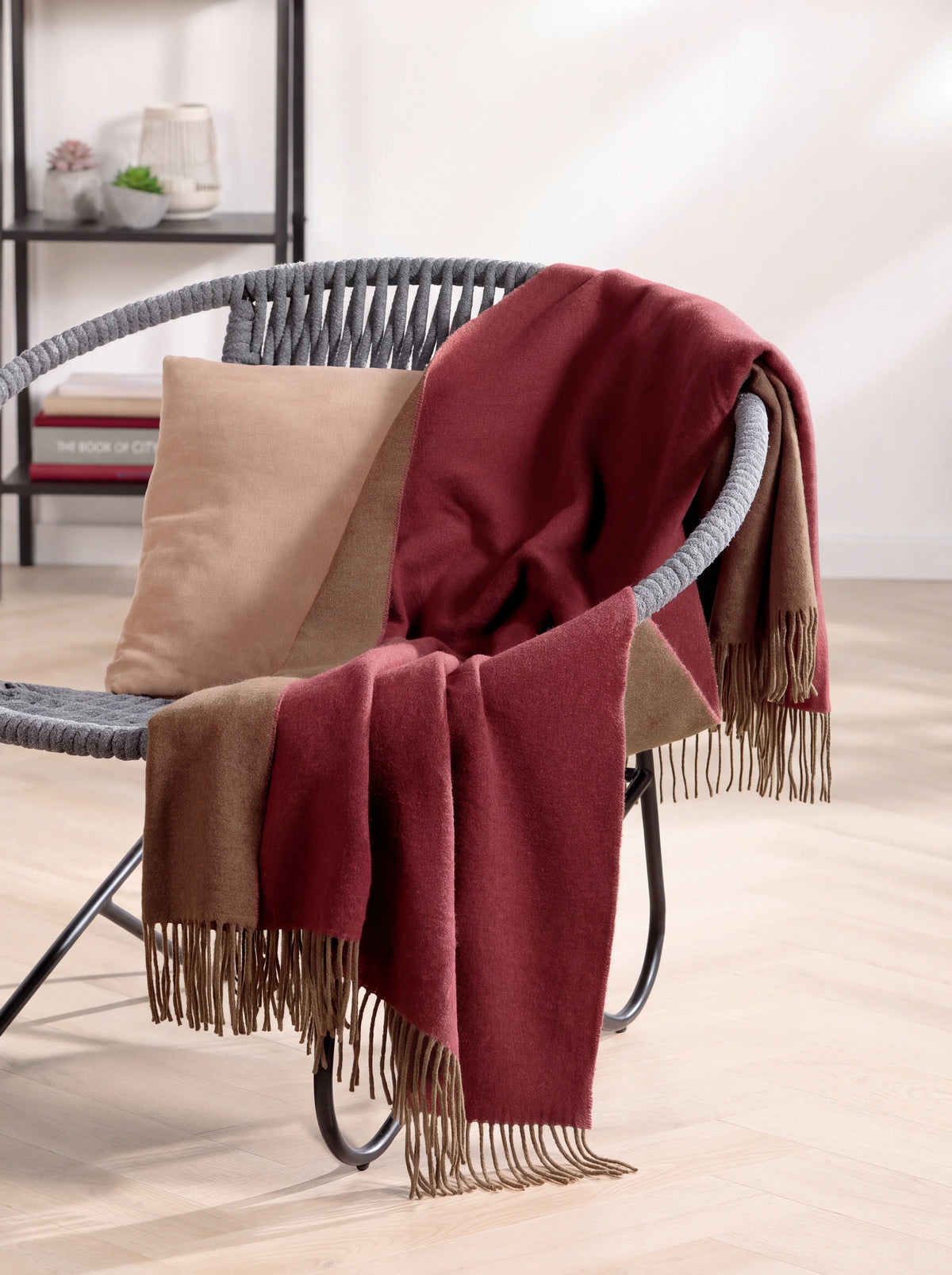 Wool and cashmere throw draped loosely over an armchair, showing both colours and fringed ends