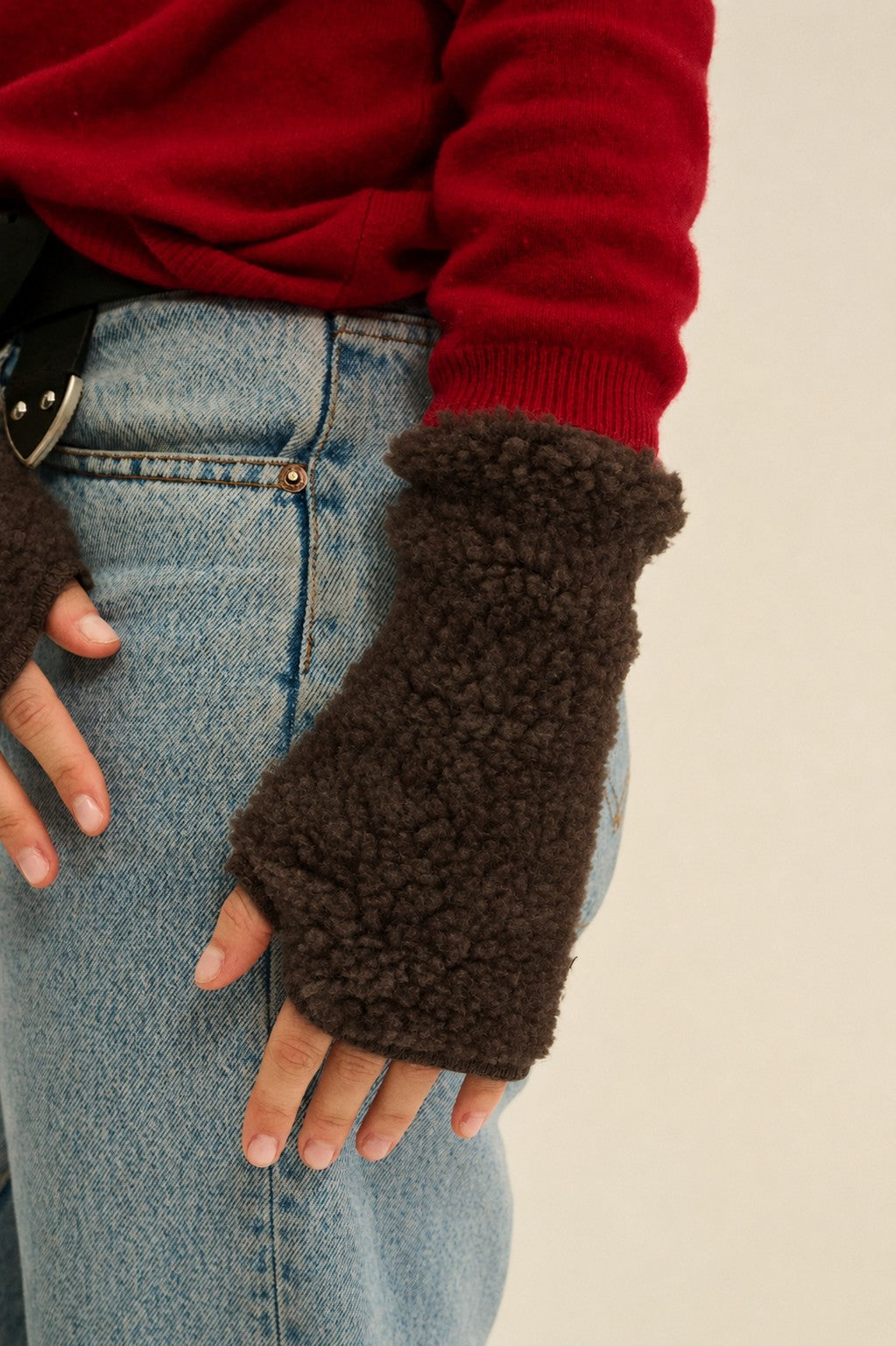 Dark brown curly wool fleece pulse warmers worn on the hand, showing the textured surface