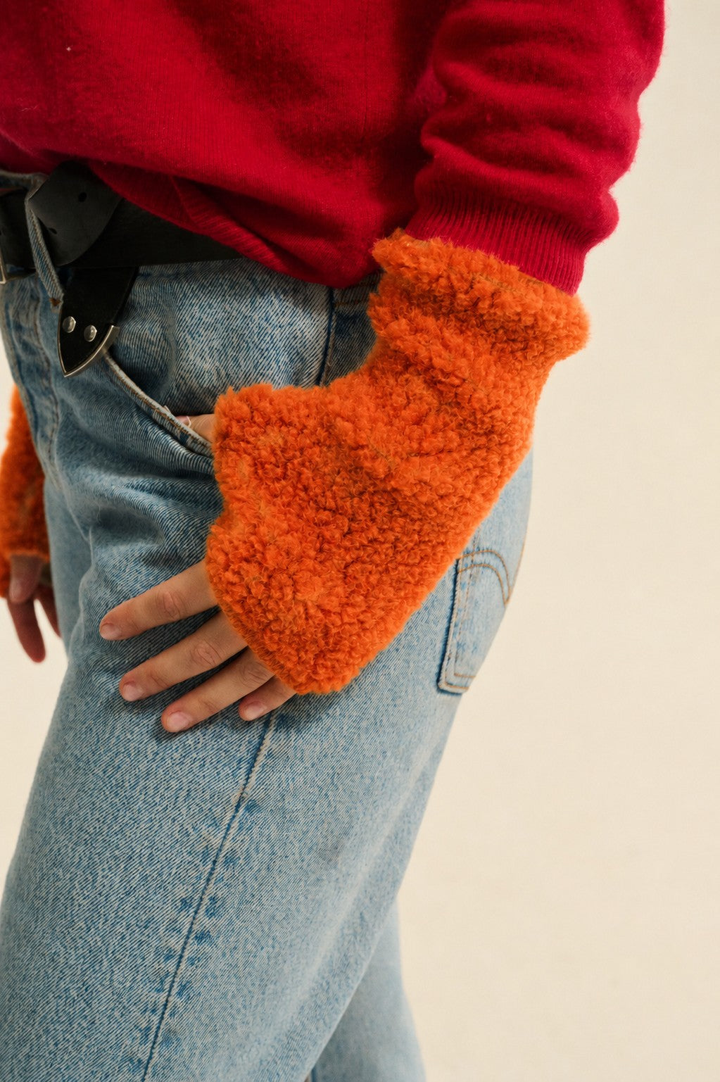 Mandarin orange wool pulse warmers with textured fleece finish, worn on the wrist and hand