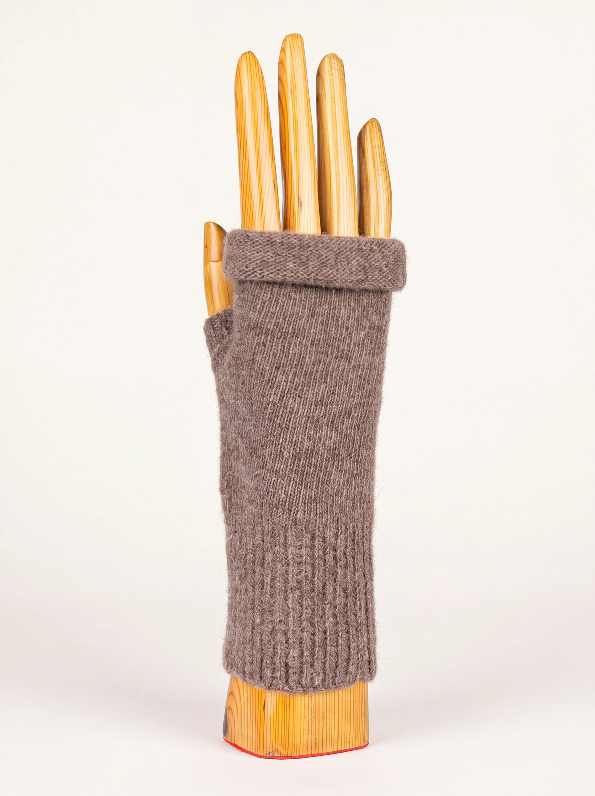 Taupe knitted wool and cashmere wrist warmer with a ribbed cuff and rolled hem, shown on a wooden hand