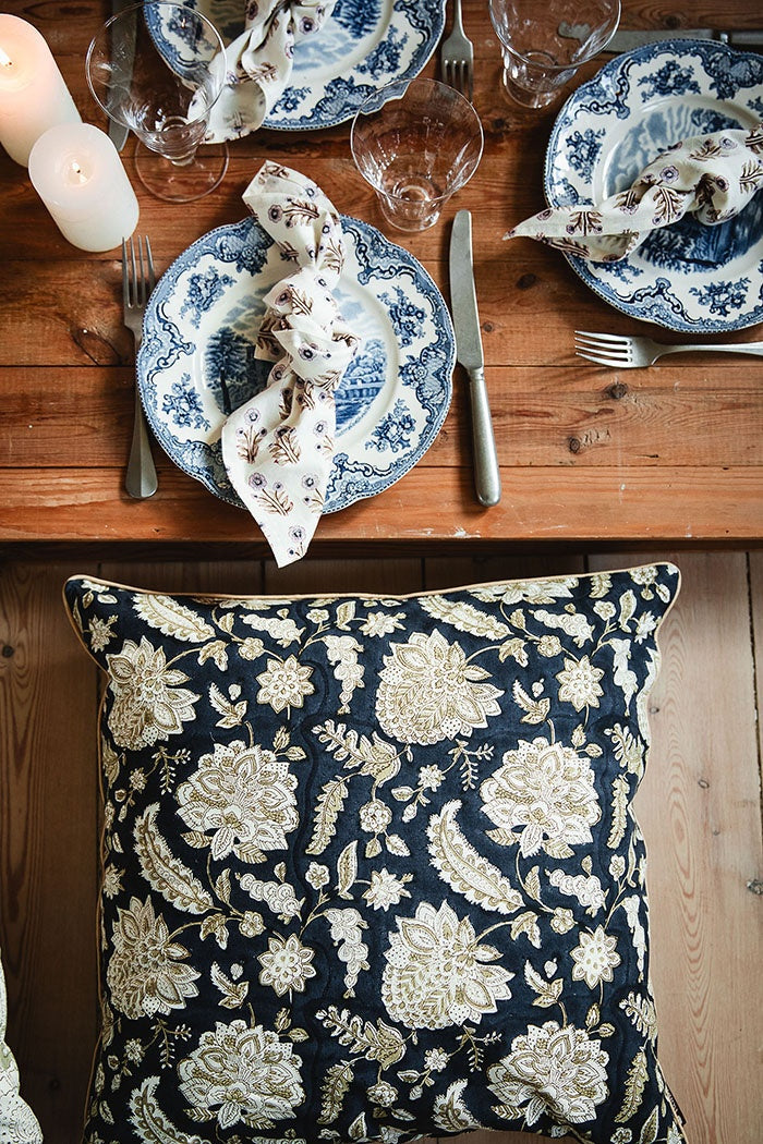 Midnight blue floral cushion on a wooden seat beside a set dining table