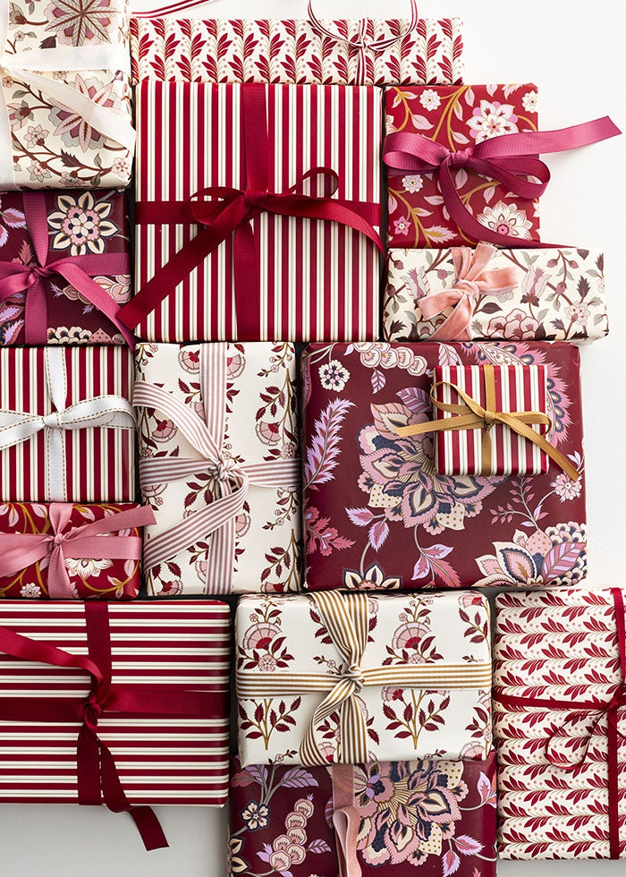 Presents wrapped in wine red floral paper and ribbon, shown alongside coordinating patterned gift boxes