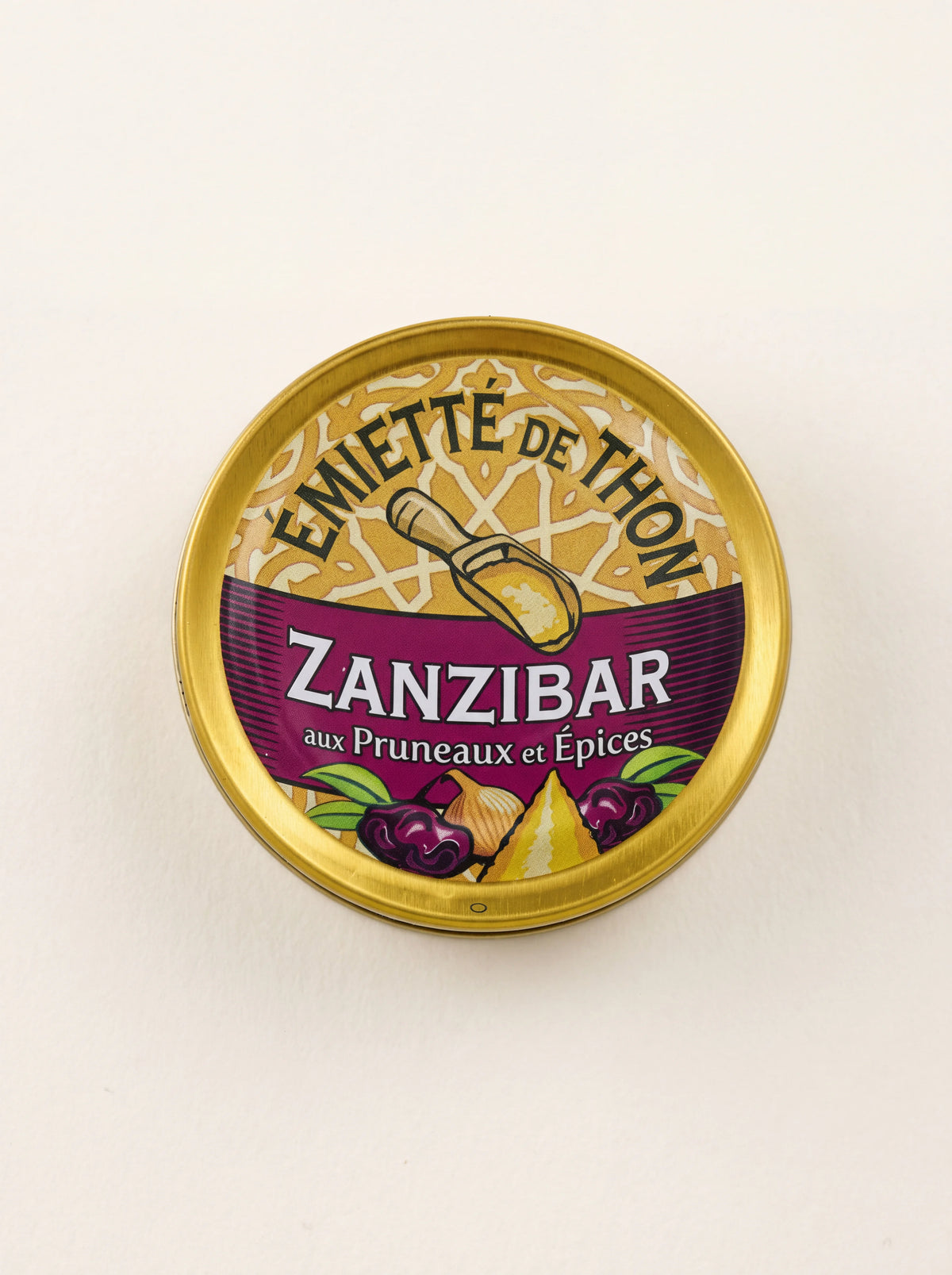 Round tin lid of flaked tuna, labelled Émietté de Thon Zanzibar aux Pruneaux et Épices