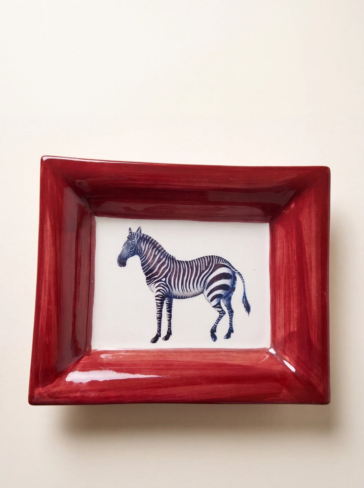 Rectangular ceramic tray with a wide red rim and painted zebra motif on a white centre